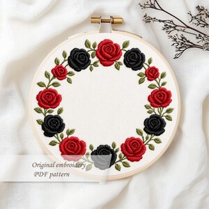 May include: An embroidery hoop featuring a floral design of red and black roses with green leaves. The roses are arranged in a circular pattern on a white fabric. The text "Original embroidery PDF pattern" is visible.
