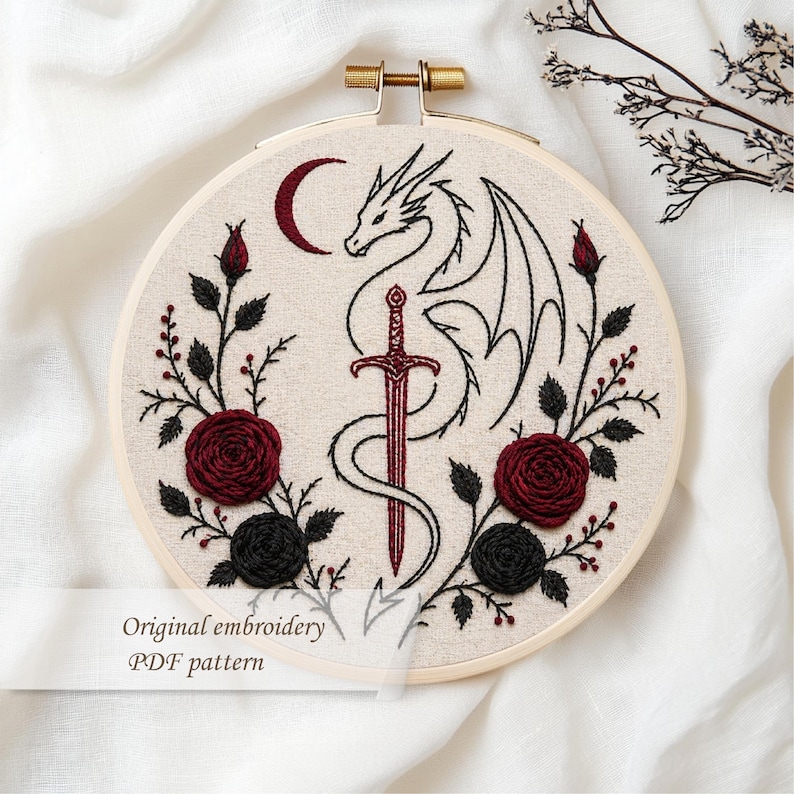 May include: Embroidered hoop art featuring a dragon, sword, and crescent moon design. The artwork includes red and black roses and the text "Original embroidery PDF pattern". The embroidery is set in a wooden hoop.