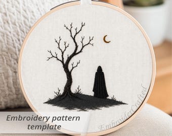 May include: An embroidery hoop featuring a black tree, a figure, and a crescent moon on a white fabric. The text "Embroidery pattern template" is visible. The design is set in a wooden hoop.