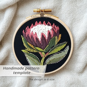 Puede incluir: Bordado a mano de una flor de protea en un aro de madera. La flor tiene pétalos blancos, rosas y burdeos con hojas verdes sobre un fondo negro. El texto dice "Handmade pattern template" y "The design in 6 size."