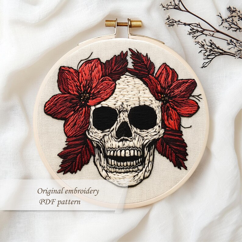 May include: An embroidered skull with red flowers and leaves, set in a wooden hoop. The skull is white with black eye sockets and a detailed jawline. The text "Original embroidery PDF pattern" is visible.