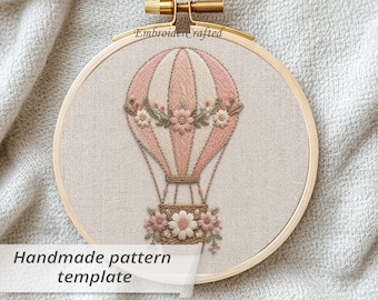 May include: A handmade embroidery pattern template featuring a hot air balloon design. The balloon is pink and white, adorned with floral accents. The text "Handmade pattern template" and "The design in 6 size" are visible.