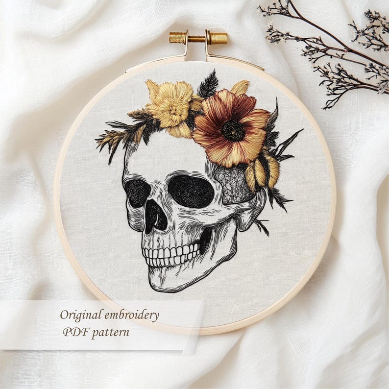 May include: An embroidery hoop featuring a detailed skull design adorned with a floral crown in shades of yellow and orange. The text "Original embroidery PDF pattern" is displayed at the bottom.