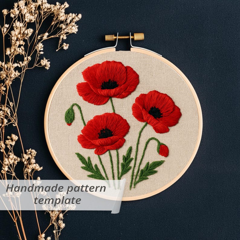 May include: An embroidery hoop featuring three red poppy flowers with black centers and green stems and leaves. The text "Handmade pattern template" is visible on the bottom left. The hoop is set against a dark blue background.