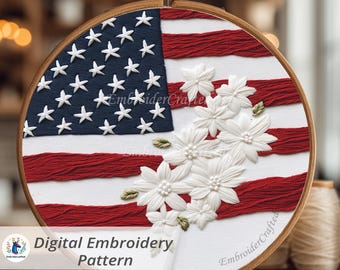 May include: A round embroidery hoop featuring an American flag design with white stars on a blue background and red and white stripes. White floral embellishments are added to the design. The text "Digital Embroidery Pattern" is visible.