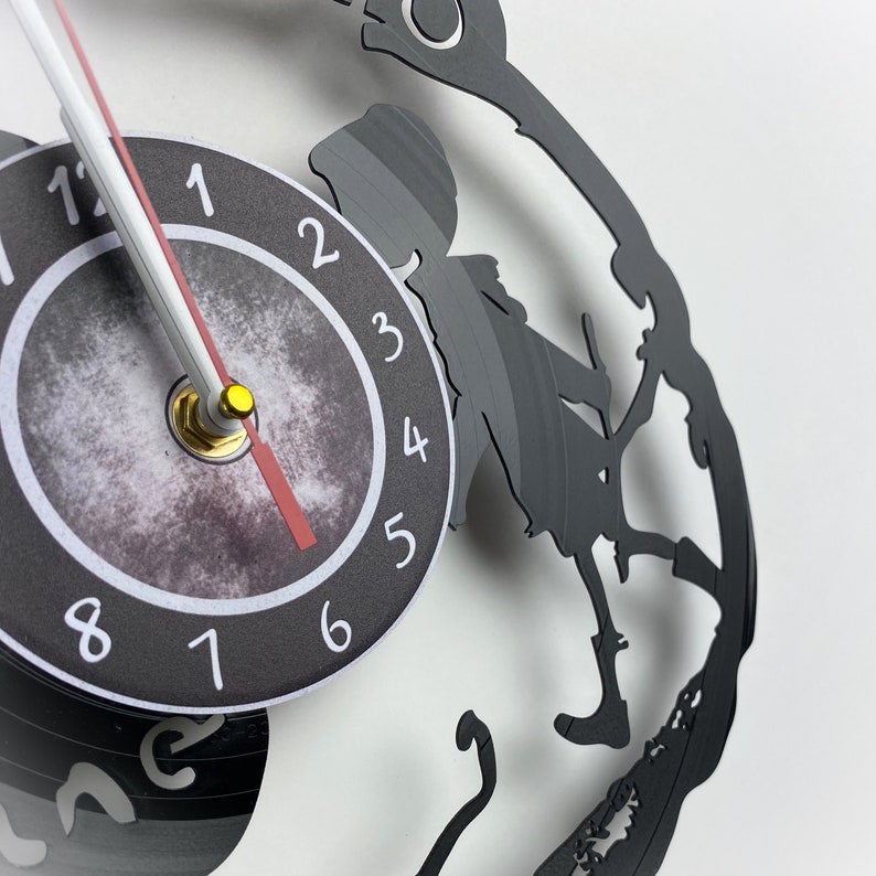 May include: Black vinyl record clock with a silhouette of a person riding a bicycle. The clock face is black with white numbers and a red hand.