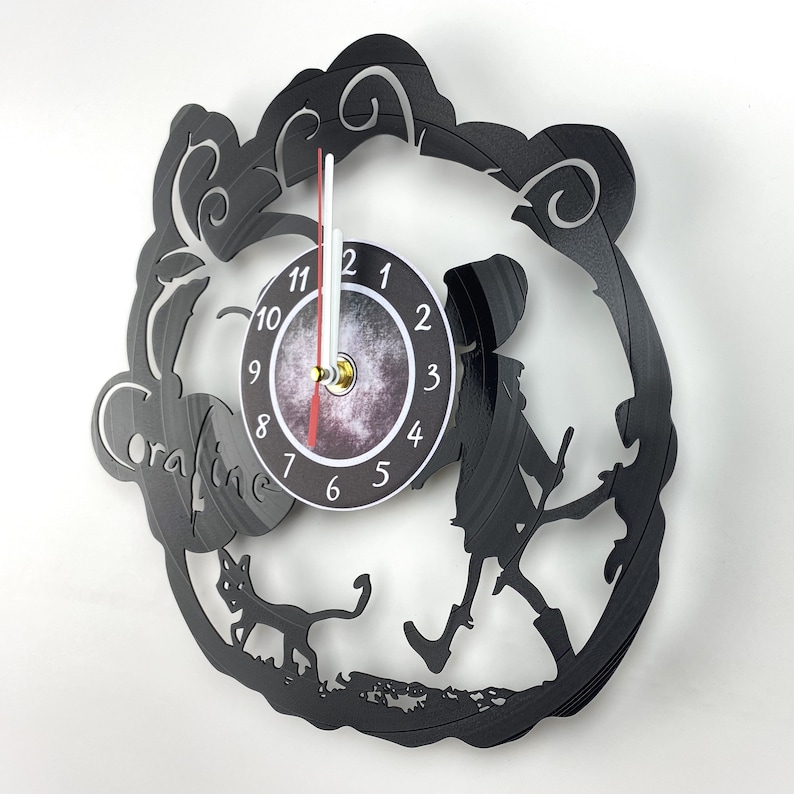 May include: Black vinyl record clock featuring a silhouette of Coraline from the movie Coraline, a black cat, and a clock face with white numbers and gold hands.