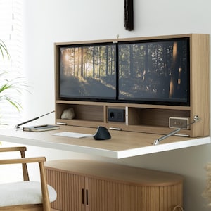 Peut inclure: Un bureau mural en bois clair avec une surface de travail rabattable, comprenant une étagère intégrée avec deux écrans d'ordinateur, une prise électrique et un port USB. Sous le bureau se trouve un meuble en bois clair à lattes verticales.