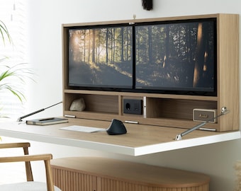 May include: A wall-mounted light wood desk with a fold-down work surface, featuring an integrated shelf with two computer monitors, a power outlet, and a USB port. Below the desk sits a light wood cabinet with vertical slats and two doors.