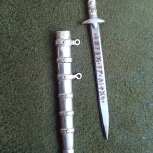 May include: A silver sword and scabbard with a decorative design and inscription. The inscription reads "S.P.Q.R. ALIXA".
