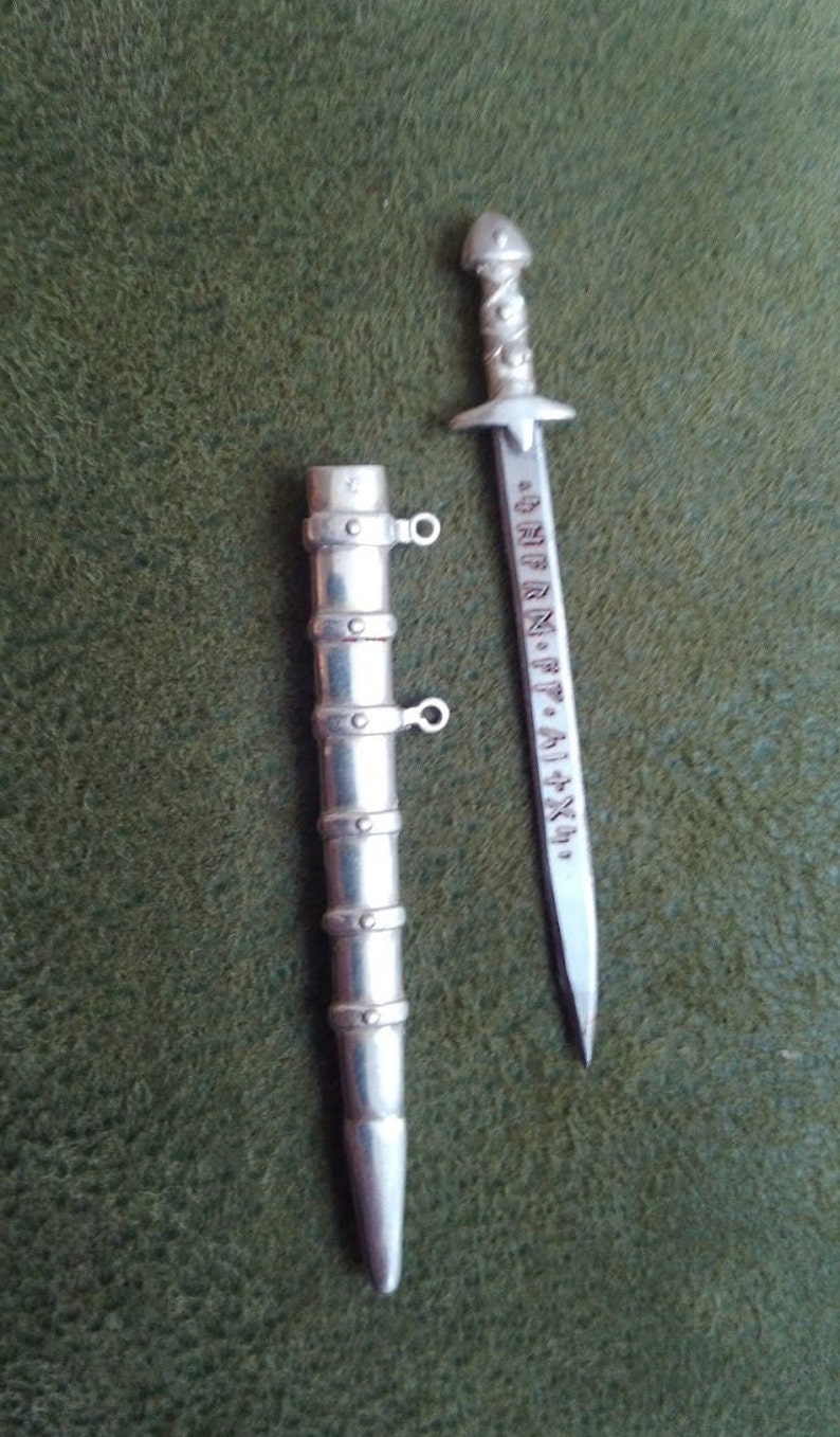 May include: A silver sword and scabbard with a decorative design and inscription. The inscription reads "S.P.Q.R. ALIXA".