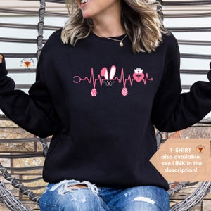 May include: Black sweatshirt with a pink Easter bunny, stethoscope, and a nurse's heart beat graphic. The text "T-SHIRT also available. see LINK in the description!" is at the bottom right corner of the image.