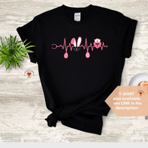 May include: Black t-shirt with a pink Easter bunny, a pink heart with a stethoscope and a nurse's hat, and a pink Easter egg on each side of the heart. The design is a heartbeat graphic. The text "T-SHIRT also available. see LINK in the description!" is at the bottom of the image.