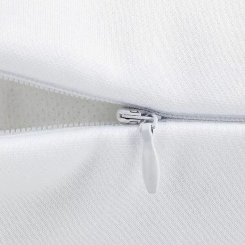 May include: A white zipper closure on a pillow cover.