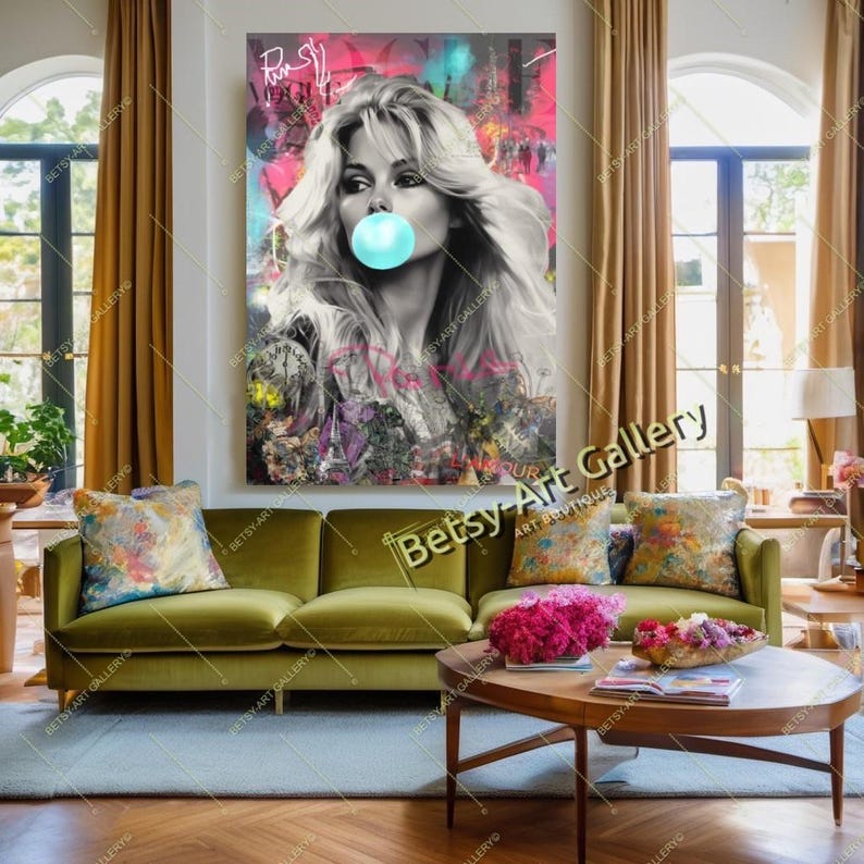 May include: A large wall art print featuring a black and white portrait of a woman blowing a bubblegum bubble. The artwork has colorful accents and the text "Betsy Art Gallery" is visible. The print hangs above a green velvet sofa.