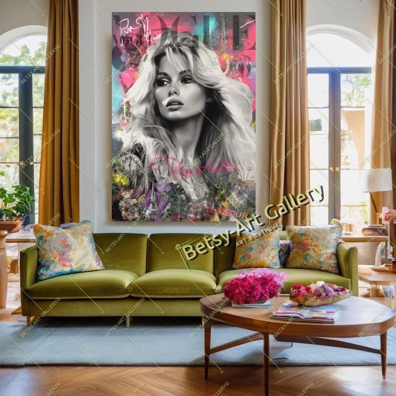 May include: A large, framed artwork featuring a black and white portrait of a woman with long, flowing hair. The background has splashes of pink, teal, and purple. The artwork hangs above a green velvet sofa with floral pillows.
