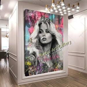 May include: A large framed canvas art print featuring a black and white portrait of a woman with long, wavy blonde hair. The background has colorful graffiti-style elements with the text "Betsy-Art Gallery". The artwork is displayed in a white-walled hallway.