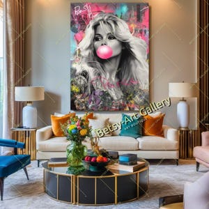 May include: A large pop art style canvas print featuring a black and white portrait of a woman blowing a pink bubblegum bubble. The background is a colorful mix of graffiti and abstract art. The print is displayed above a white sofa.
