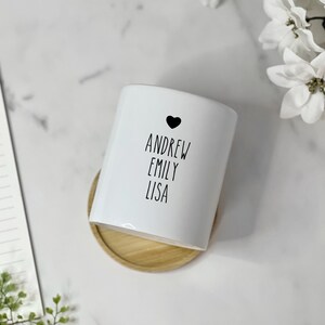 May include: White ceramic planter with a black heart and the names Andrew, Emily, and Lisa written in black.