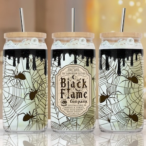 Op de afbeelding: Drie zwart-witte Halloween-bekers met deksels en rietjes. De bekers hebben een spinnenwebontwerp met zwarte spinnen en druipende zwarte verf. De middelste beker heeft een etiket met de tekst "EST. 1693 - THE SANDERSON SISTERS Black Flame Company. SPECIALIZING IN CANDLES & CURSES MADE WITH GENUINE HOCUS POCUS."