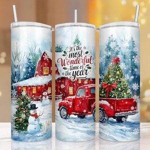 May include: Three stainless steel tumblers with a winter holiday theme. The tumblers feature a red truck, a snowman, and a Christmas tree. The text on the tumbler reads "It's the most wonderful time of the year."