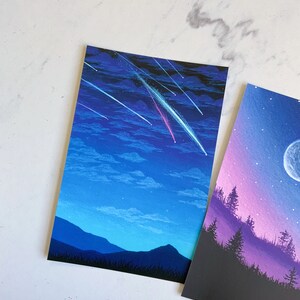 Puede incluir: Una pintura de un cielo nocturno con estrellas fugaces y una cordillera en la distancia. El cielo es de un azul profundo con nubes blancas y las monta&ntilde;as est&aacute;n silueteados contra el cielo.