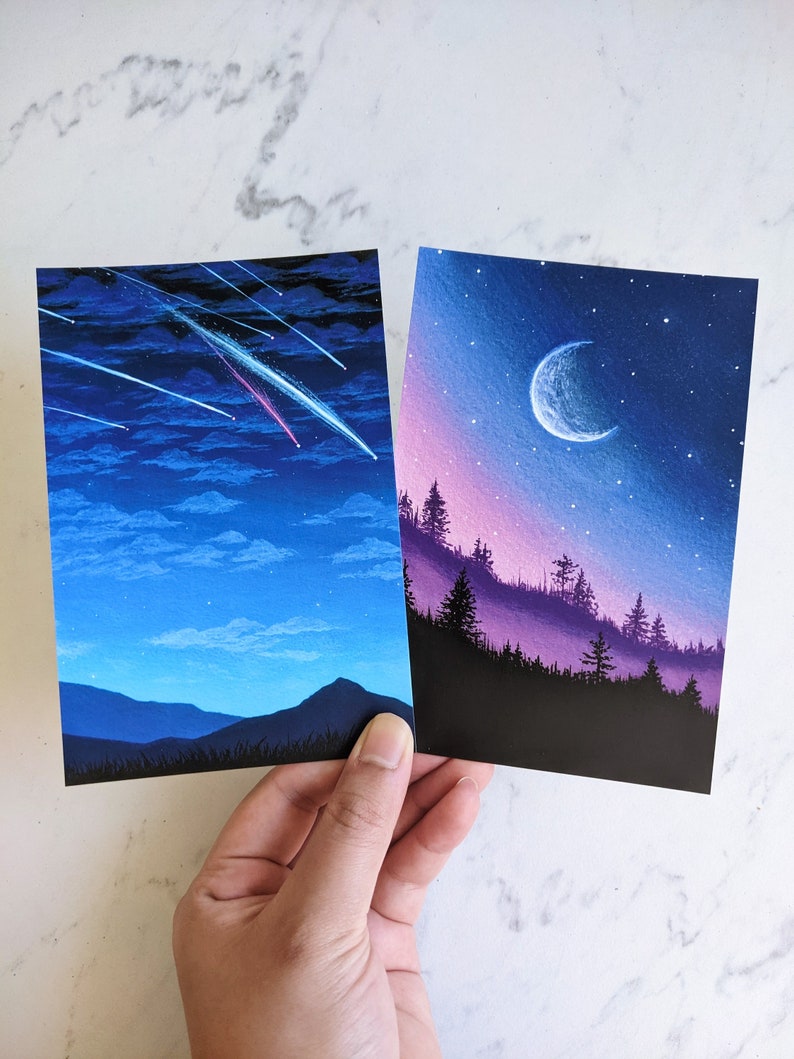 Puede incluir: Dos pinturas de cielos nocturnos con estrellas. La primera pintura muestra un cielo azul oscuro con una estrella fugaz rosa y blanca. La segunda pintura muestra un cielo azul oscuro con una luna creciente y un horizonte morado y rosa.