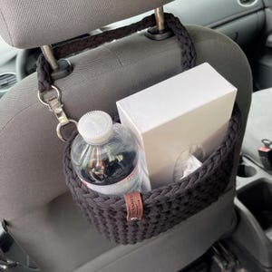In the photo is a basket crocheted from t-shirt yarn, which can be hung on the headboard of the car seat. The strap is attached with a strong metal button. Suitable for collecting small trash or for storing napkins, water or other personal items.
