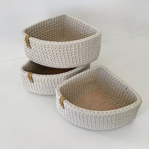 May include: Three white crocheted corner shelves with wooden bottoms. The shelves are stacked on top of each other.