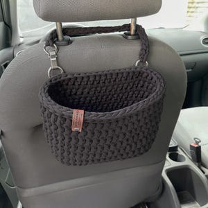 In the photo is a basket crocheted from t-shirt yarn, which can be hung on the headboard of the car seat. The strap is attached with a strong metal button. Suitable for collecting small trash or for storing napkins, water or other personal items.