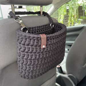 In the photo is a basket crocheted from t-shirt yarn, which can be hung on the headboard of the car seat. The strap is attached with a strong metal button. Suitable for collecting small trash or for storing napkins, water or other personal items.