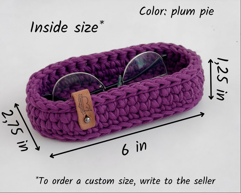 The photo shows a small oval-shaped knitted tray. On the side of the tray is a leather tag with the inscription "Made with love".