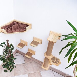 May include: A wooden cat tree with a bed, scratching post, and multiple platforms. The cat tree is mounted on a white wall and has a brown cushion in the bed.