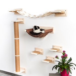 Pode incluir: Uma &aacute;rvore para gatos com uma variedade de plataformas e uma rede para os gatos relaxarem. A &aacute;rvore para gatos &eacute; feita de madeira e tem um acabamento natural. A &aacute;rvore para gatos est&aacute; montada em uma parede branca.