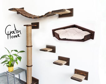 May include: A brown wooden cat tree with a bridge, a scratching post, and a bed. The cat tree is mounted on a white wall. The text "Gratsy Home" is written on the wall.