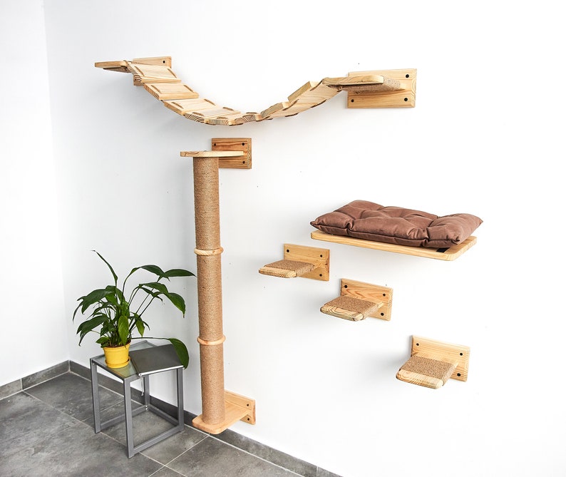 Pu&ograve; includere: Un albero per gatti in legno con un ponte, un tiragraffi e diverse piattaforme. Le piattaforme sono ricoperte di corda di sisal e il ponte &egrave; fatto di assi di legno. L'albero per gatti &egrave; montato su una parete bianca.