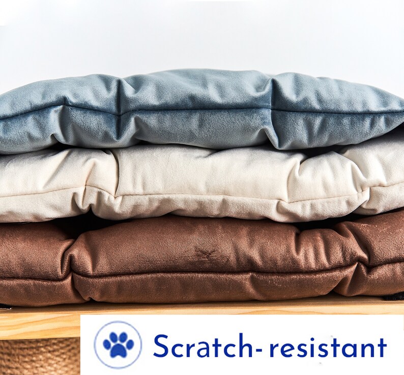 May include: Three stackable cushions in brown, beige, and blue velvet. The cushions are scratch-resistant.