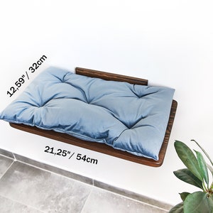 May include: A light blue, tufted cat bed mounted on a dark wood shelf. The shelf is 21.25 inches wide and 12.59 inches deep.