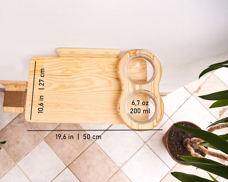 May include: A wooden cat feeder with two glass bowls. The feeder is 19.6 inches wide and 10.6 inches tall. The bowls are 6.7 ounces each and hold 200 ml of food or water.