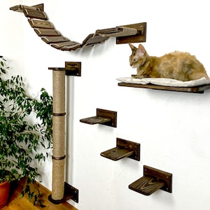 Pu&ograve; includere: Un albero per gatti a parete con un palo per grattare rivestito in sisal, un ponte e pi&ugrave; ripiani. Un gatto &egrave; seduto su uno dei ripiani.