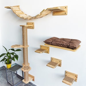 May include: A wooden cat tree with a scratching post, a bridge, and a bed. The cat tree is mounted on a white wall. The bridge is curved and has a natural wood finish. The bed is rectangular and has a brown cushion. The cat tree is made of natural wood and has a rustic look.
