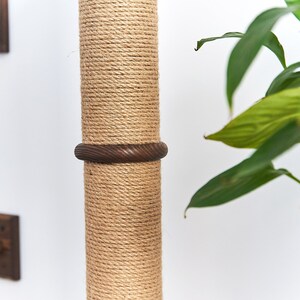 May include: Close-up of a natural sisal rope-covered scratching post for cats. The post has a brown wooden ring around it.