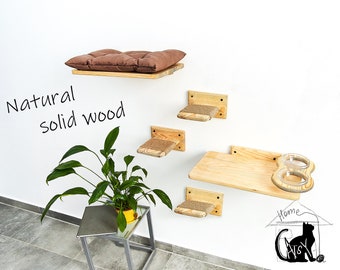Può includere: Un set di mensole in legno per gatti montate su una parete bianca. Le mensole sono realizzate in legno massello naturale e presentano un cuscino marrone, tiragraffi in corda di sisal e una doppia ciotola per il cibo. Le mensole sono disposte a gradini, con la mensola superiore che è la più grande e la mensola inferiore che è la più piccola. Le mensole sono progettate per fornire ai gatti una varietà di posti dove appollaiarsi, giocare e dormire.