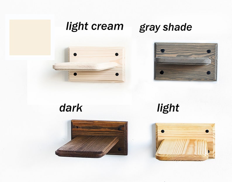 May include: Four wooden cat shelves in different colors: light cream, gray shade, dark brown, and light wood. Each shelf is mounted on a wall and has a small platform for cats to perch on.