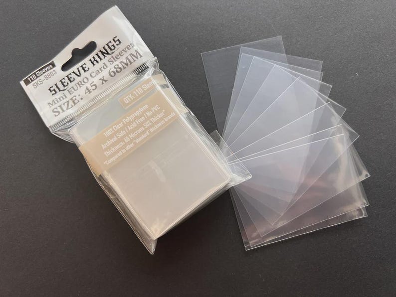May include: A package of clear plastic card sleeves with the text "SLEEVE KINGS" and "Mini EURO Card Sleeves" with dimensions of 45 x 68mm. A stack of individual sleeves is fanned out beside the package. The package contains 110 sleeves.