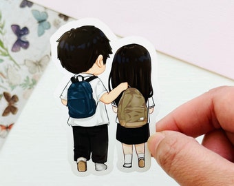 May include: A sticker featuring a cartoon illustration of a boy and girl walking side-by-side. The boy is wearing a white shirt, blue pants, and a blue backpack. The girl is wearing a white shirt, a black skirt, and a brown backpack. They are both looking forward.