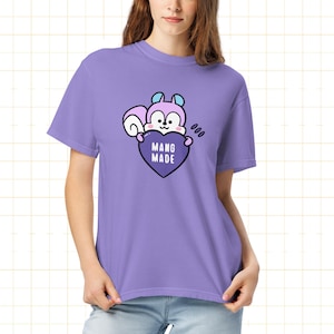 May include: A lilac-colored t-shirt featuring a cartoon squirrel holding a purple heart with the words "MANG MADE." The squirrel has light blue accents and the shirt has a relaxed fit.
