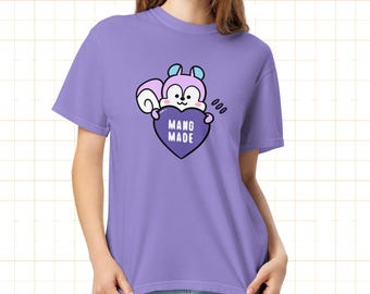 May include: A lilac-colored t-shirt featuring a cartoon squirrel holding a purple heart with the words "MANG MADE." The squirrel has light blue accents and the shirt has a relaxed fit.