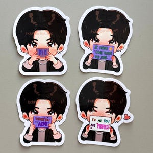May include: Four die-cut stickers featuring a cartoon character with black hair, wearing a black jacket and silver chain. Each sticker shows the character holding a sign with text: BYE, I HAVE ONE THING TO SAY, THANK YOU ARMY, and TO ME YOU ARE PERFECT.