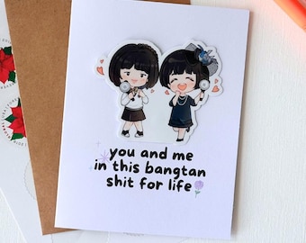 May include: A white card with a purple flower and the text "you and me in this bangtan shit for life" printed on it. Two cartoon girls with microphones are on the card.